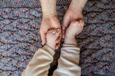 Hände die Babyfüße halten